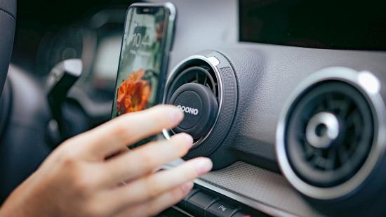 Smartphone-Halterung für das Auto-Lüftungsgitter Nahaufnahme einer Hand, die ein Smartphone in eine Auto-Lüftungs-Halterung einsetzt