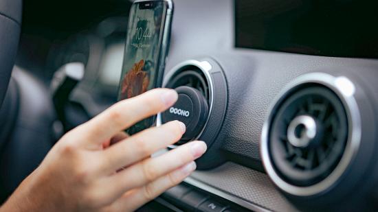 Magnetische Handyhalterung im Auto für Lüftungsschlitze Hand befestigt ein Smartphone an einer magnetischen Autohalterung in den Lüftungsschlitzen