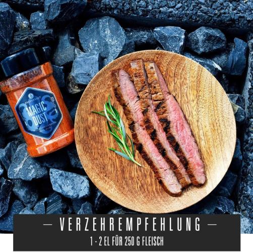 Holzteller mit gegrilltem Fleisch, Gewürz namens Magic Dust daneben, auf Kohlen arrangiert