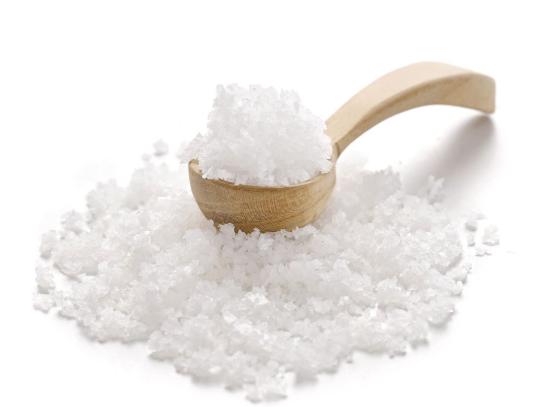 Ein Holzlöffel mit feinem Meersalz auf hellem Hintergrund