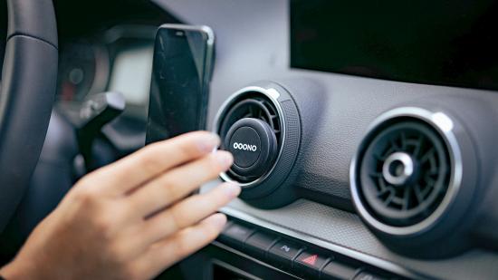 Smartphone-Halterung in einem Auto an der Lüftung Nahaufnahme einer Hand, die ein Smartphone in eine Lüftungshalterung im Auto einsetzt