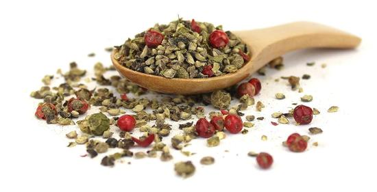 Gemischte Pfefferkörner in einem Holzlöffel auf weißem Hintergrund