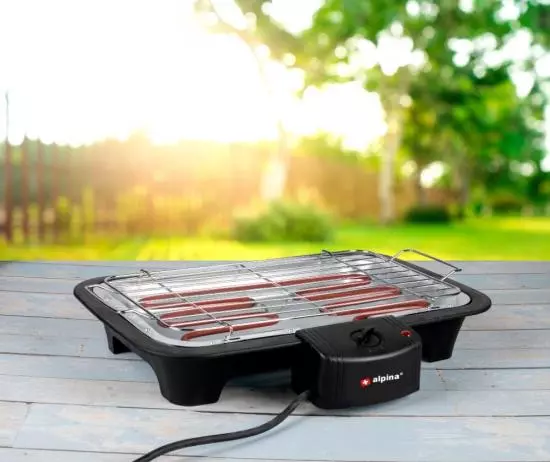 Elektrischer Tischgrill auf Holztisch im Garten