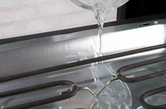 Nahaufnahme der Wasserbefüllung eines Edelstahl-Dampfbügeleisens mit Maximal- und Minimal-Markierungen